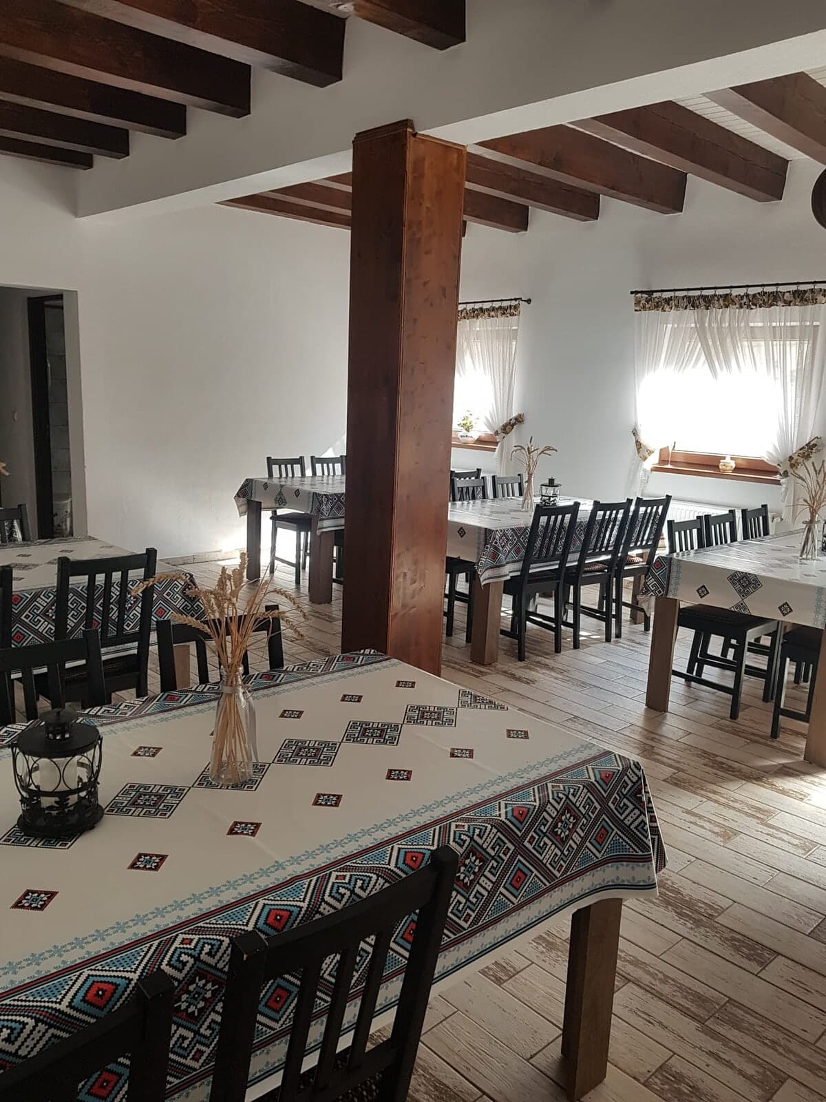 Sala de mese cu grinzi din lemn și fețe de masă cu motive tradiționale