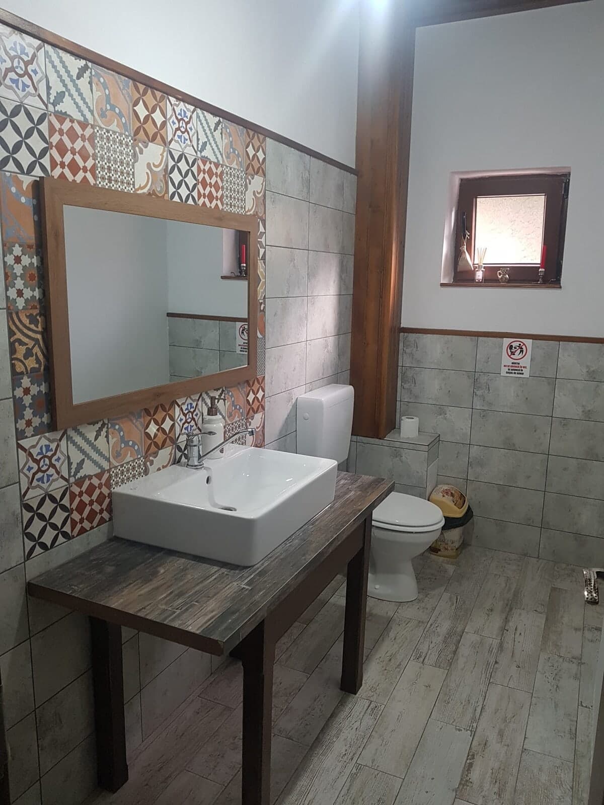 Baie cu faianță cu model și lavoar pe o masă din lemn